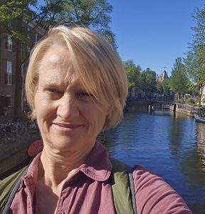 A selfie of Renee Stillings along an Amsterdam canal, with boats and trees along the water.
