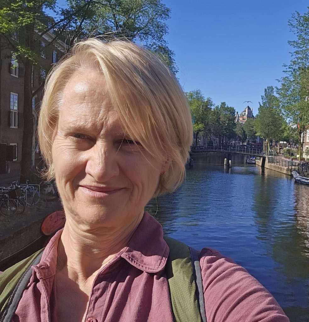 A selfie of Renee Stillings along an Amsterdam canal, with boats and trees along the water.