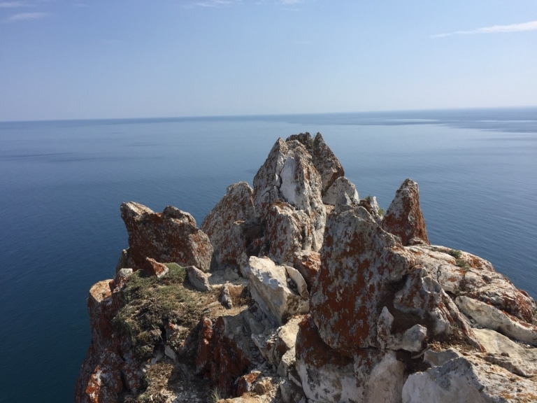 A jagged rocky outcrop overlooking the still waters of Lake Baikal.