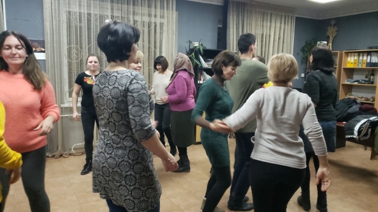 A group of people holding hands and dancing together during a traditional Ukrainian dance lesson.