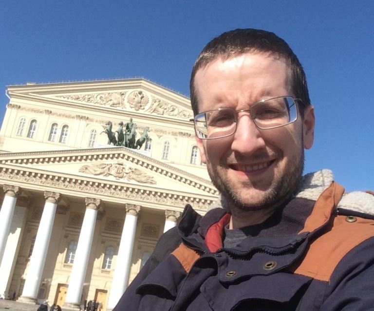Josh smiling in front of the Bolshoi Theatre in Moscow.