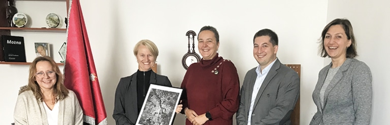 A group of five people posing together indoors after a certificate presentation ceremony.