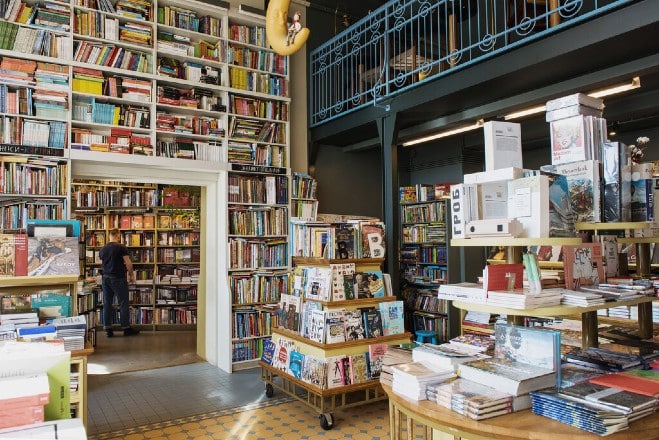 Interior of a bookstore with floor-to-ceiling shelves and a customer browsing books.