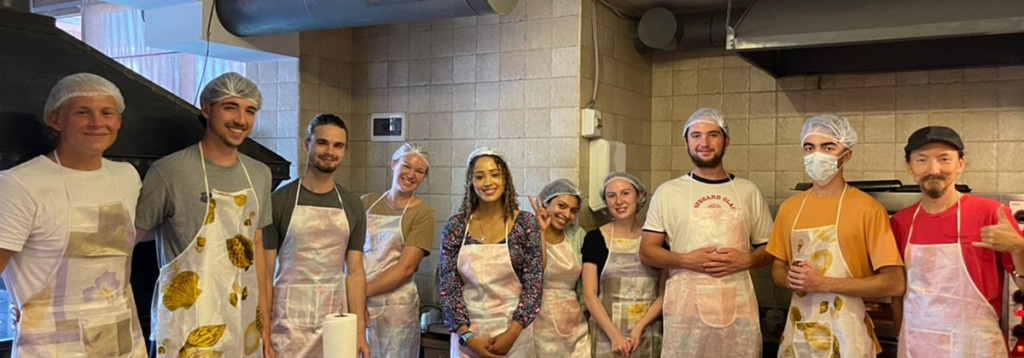 A group of students wearing aprons and hairnets during a cooking class in Georgia.
