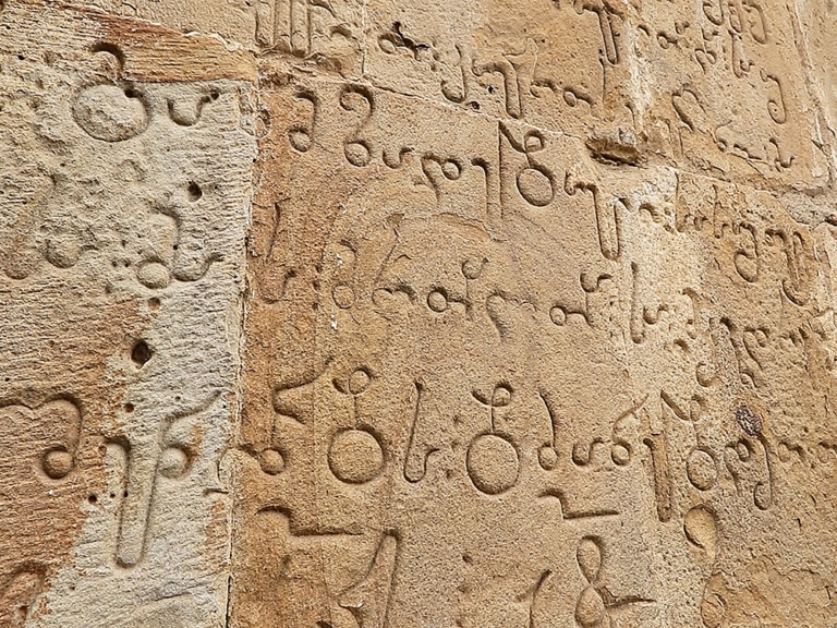 Close-up of elegant Georgian script carved into stone.