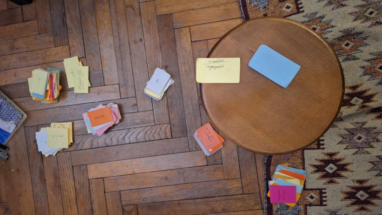 Overhead view of colorful handwritten flashcards and notecards spread across a wooden floor.