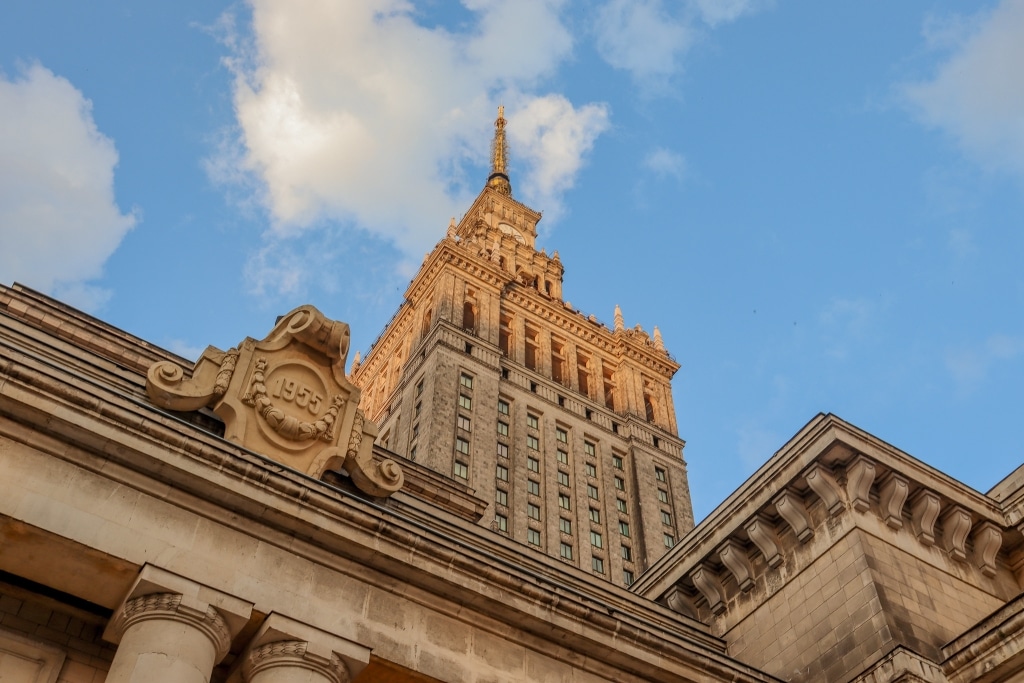 The spire of Warsaw's Palace of Culture and Science, with a "1955" cornerstone plaque visible below.