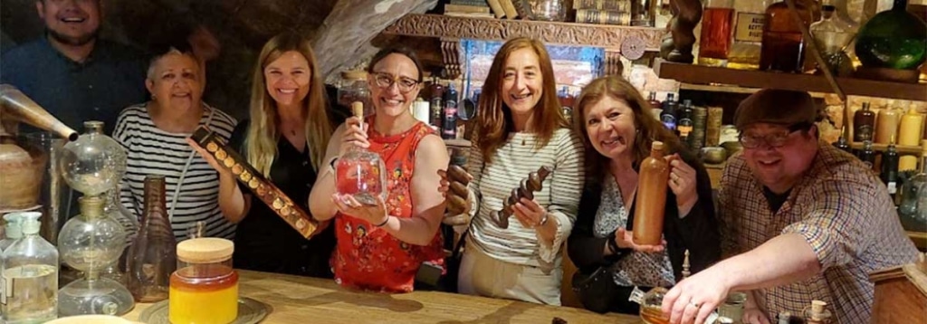 A group of people sampling drinks and holding bottles and jars during a site visit to a shop.
