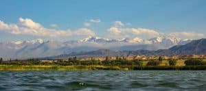the scenic shores of Issyk-Kul Lake in Kyrgyzstan, framed by the towering peaks of the Tian Shan mountain range