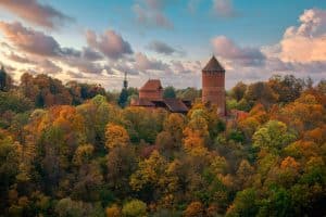 Breathtaking aerial view of Turaida Castle surrounded by vibrant autumn foliage in Sigulda, Latvia.