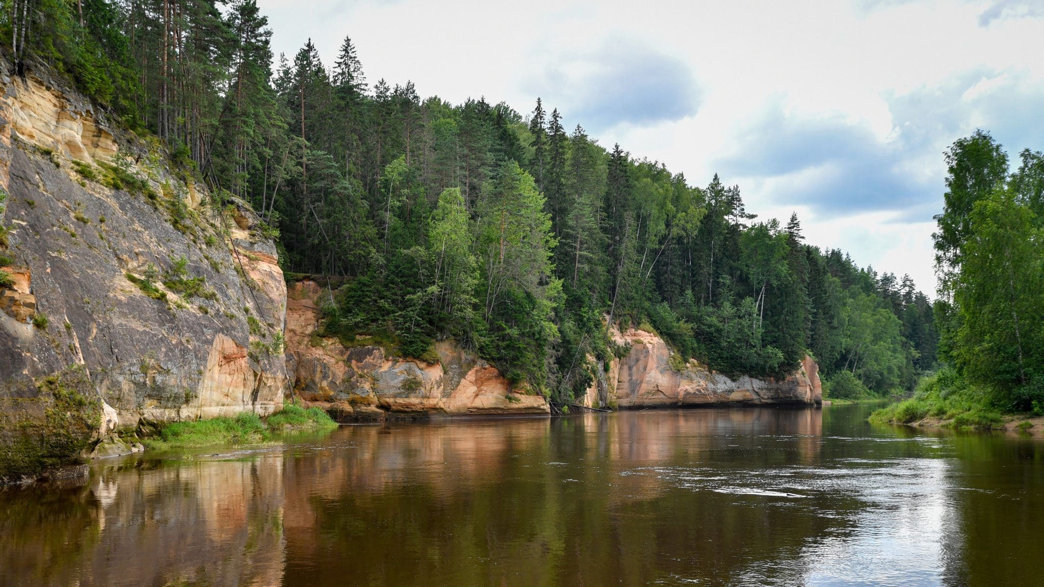 River with sandstone cliffs and lush forest on its banks.