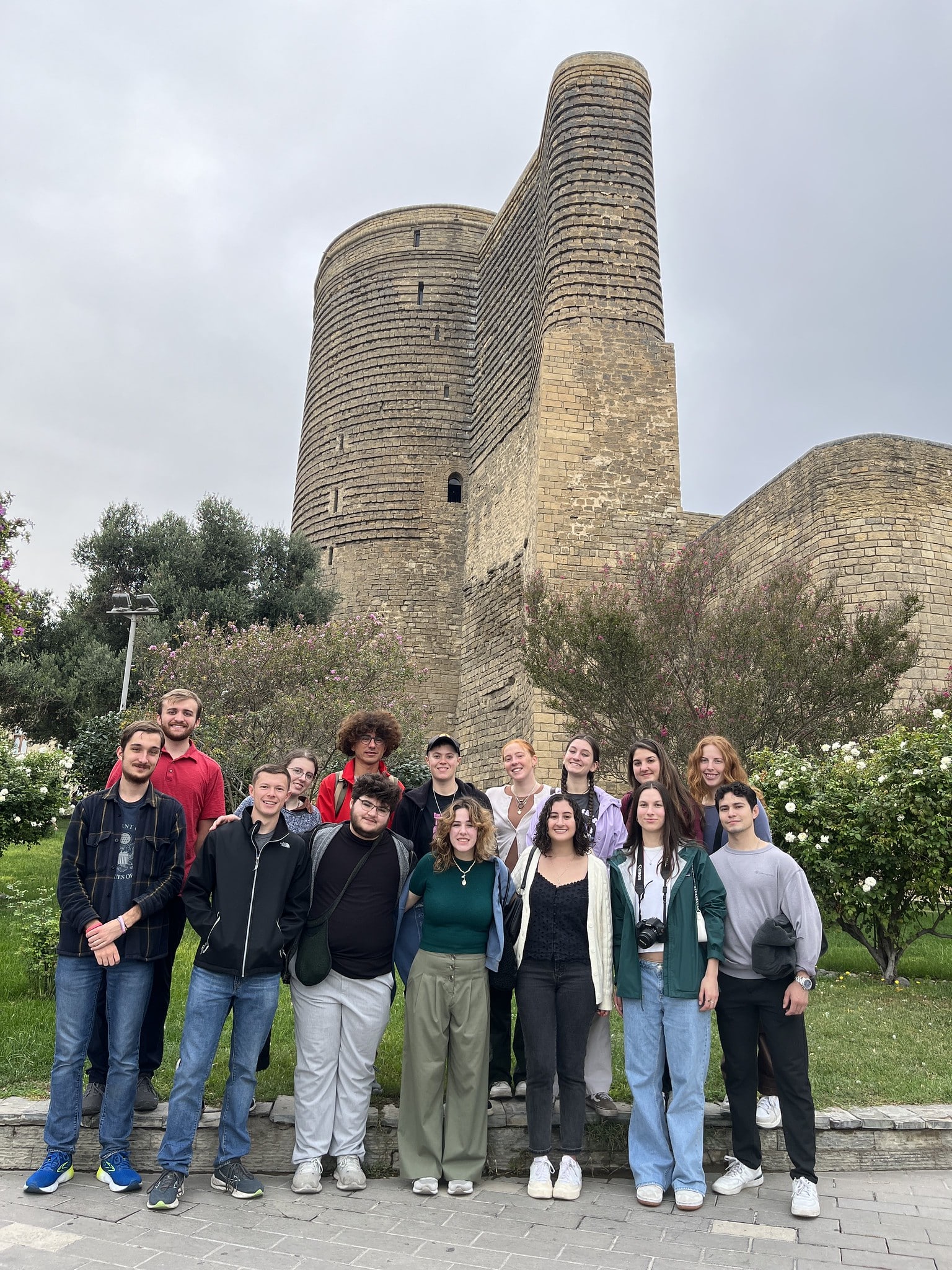 Group of smiling students standing in front of a stone tower.