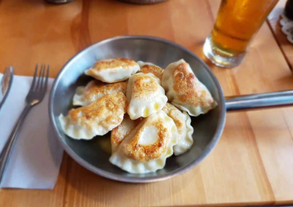 A plate of pan-fried pierogi, which are traditional Polish filled dumplings.